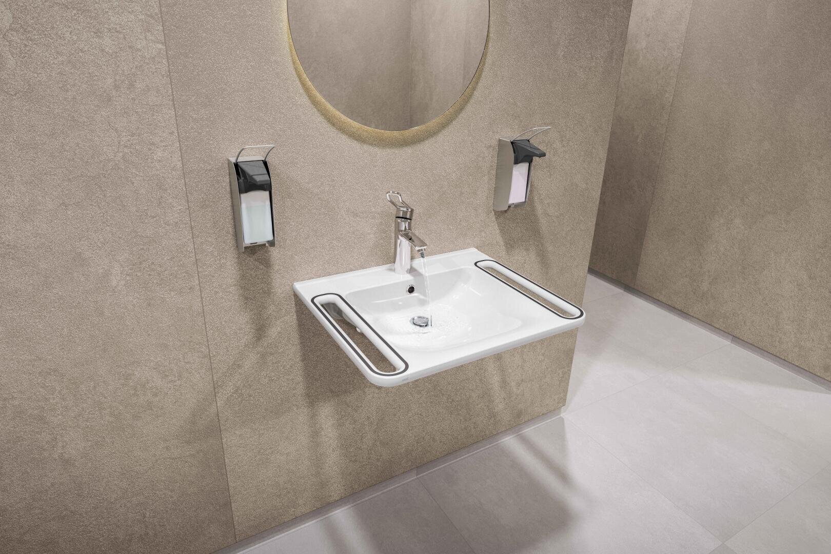 Ein modernes, barrierefreies Waschbecken mit zwei horizontalen Stützschienen, einem zentralen Wasserhahn, einem runden Spiegel und zwei Seifenspendern an einer beigen Wand in einer Toilette mit hellem Bodenbelag.