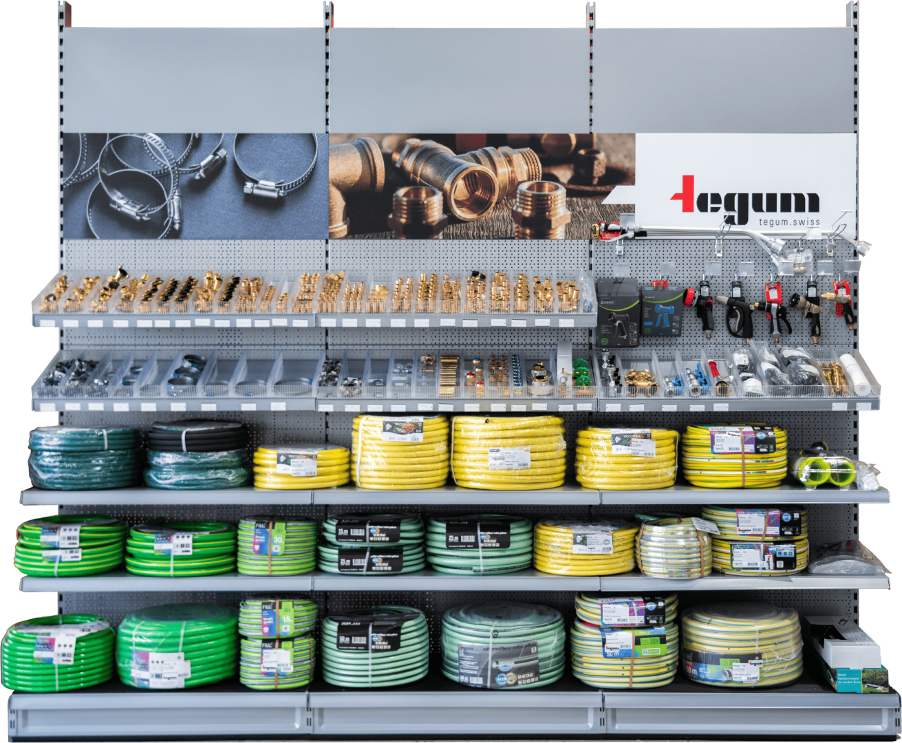 Une étagère de magasin avec des tuyaux d'arrosage verts et jaunes, des raccords de tuyaux, des colliers de serrage métalliques, des buses et des robinets. Sur le panneau supérieur, on peut voir des illustrations de pièces sanitaires et le logo de la marque Tegum.