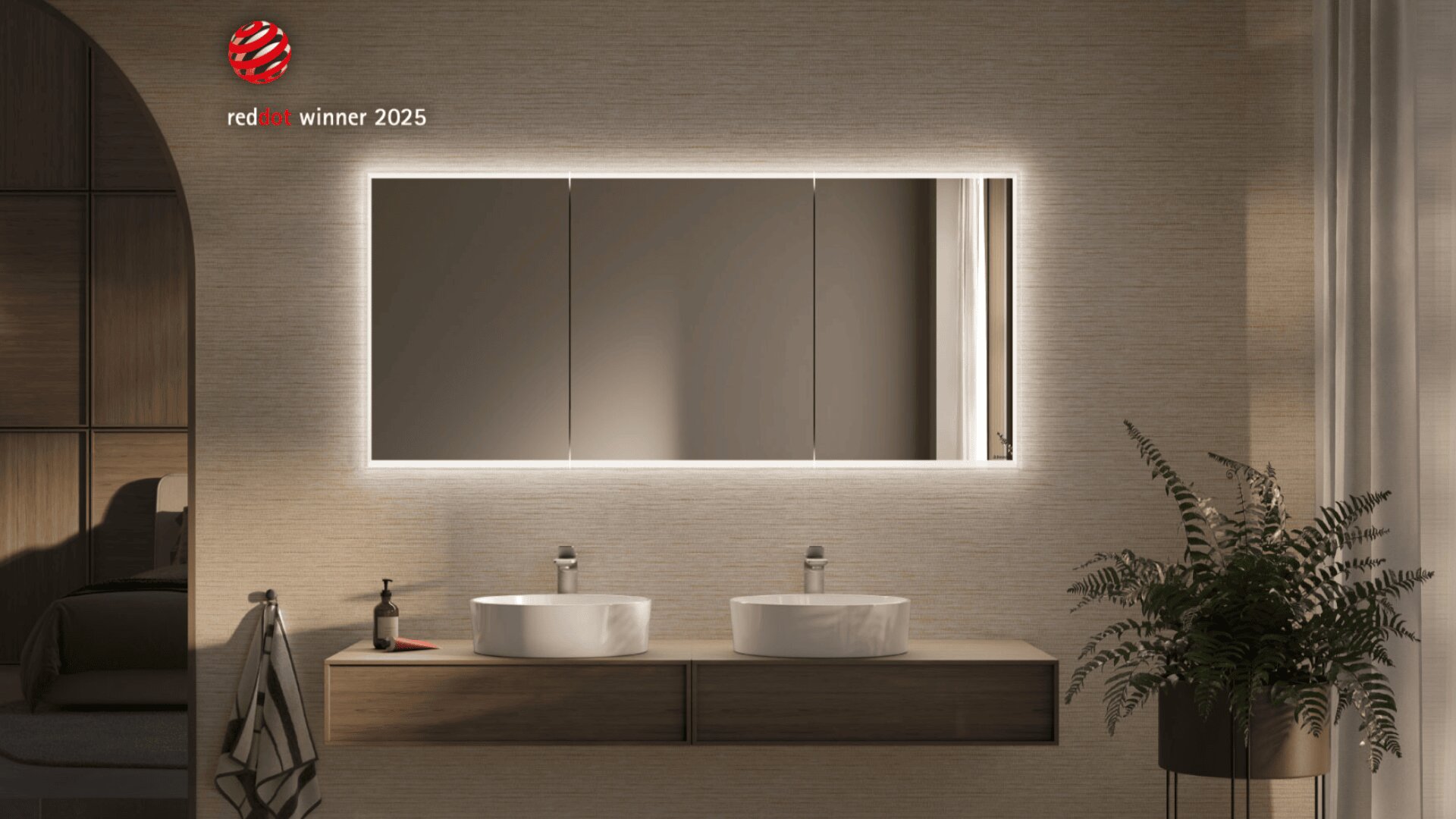 Une salle de bains moderne avec deux lavabos ronds sur un meuble en bois flottant, un grand miroir éclairé, un distributeur de savon, une serviette, une plante à droite et un logo Red Dot Award 2025 dans le coin supérieur gauche.