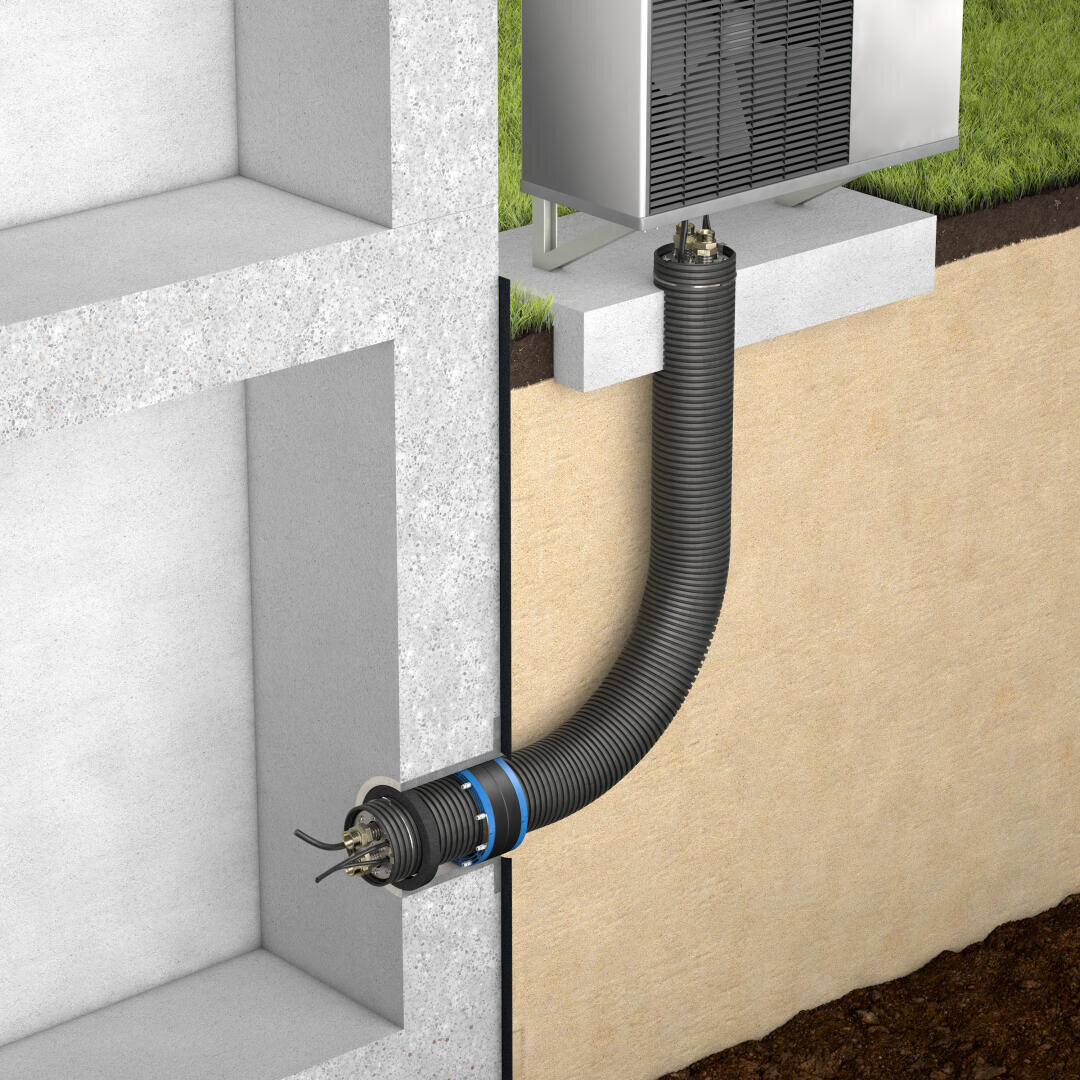 Ein schwarzes, flexibles Rohr verbindet eine Außen-HLK-Einheit mit einem Gebäudefundament und führt durch eine Betonwand und den Boden, wobei die Drähte auf der Innenseite des Rohrs sichtbar sind.