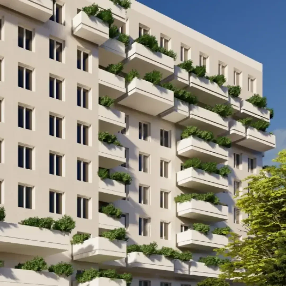 Ein modernes, mehrstöckiges Wohnhaus mit zahlreichen Balkonen, die mit Grünpflanzen geschmückt sind. Die Fassade ist in hellen Farben gehalten, und im Vordergrund steht ein belaubter Baum.