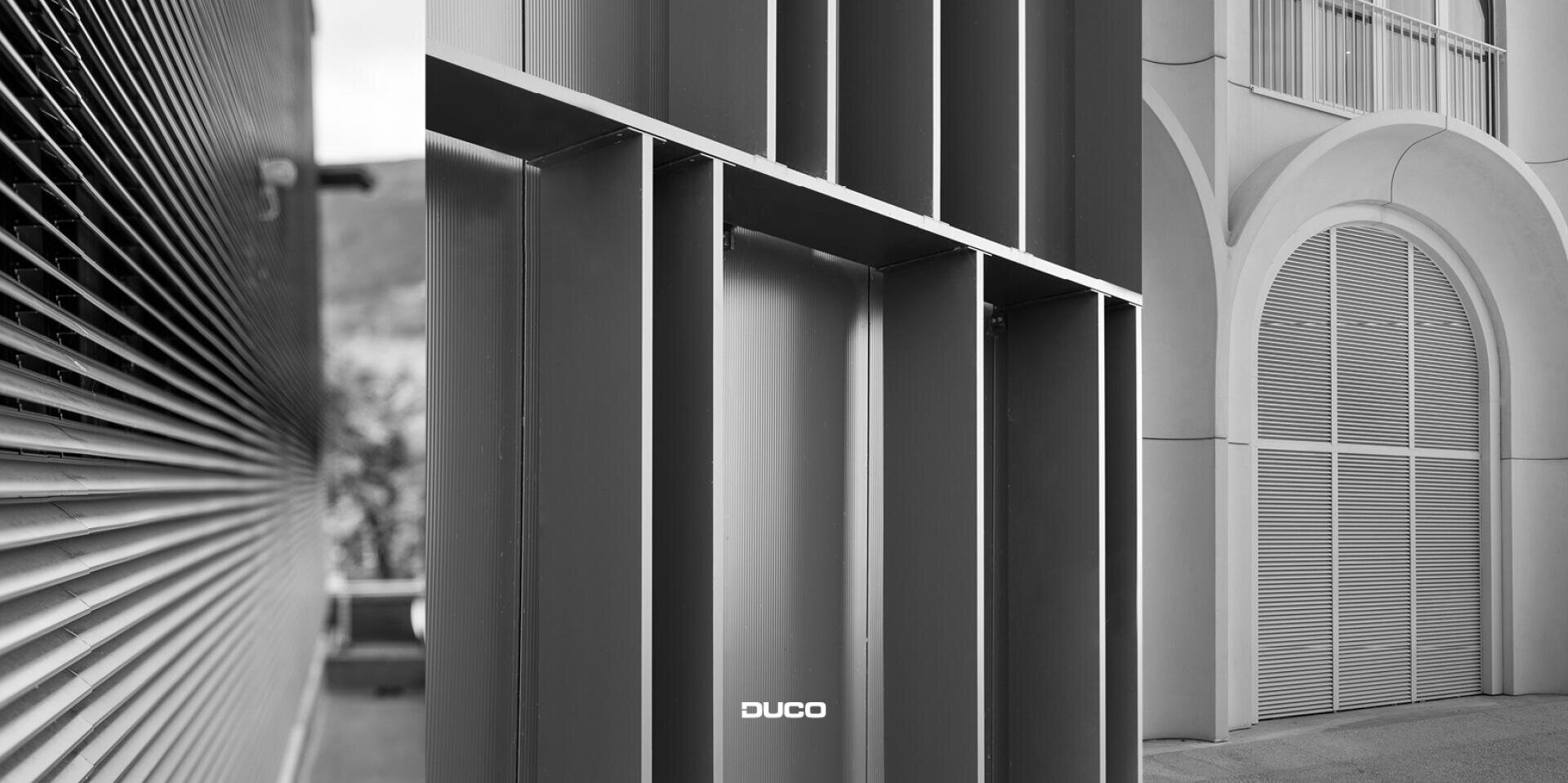 Un collage en noir et blanc de trois détails architecturaux : des lamelles métalliques horizontales à gauche, des grilles verticales et horizontales au centre et de grandes grilles métalliques en forme d'arc sur la façade d'un bâtiment à droite. DUCO est visible en bas au centre.