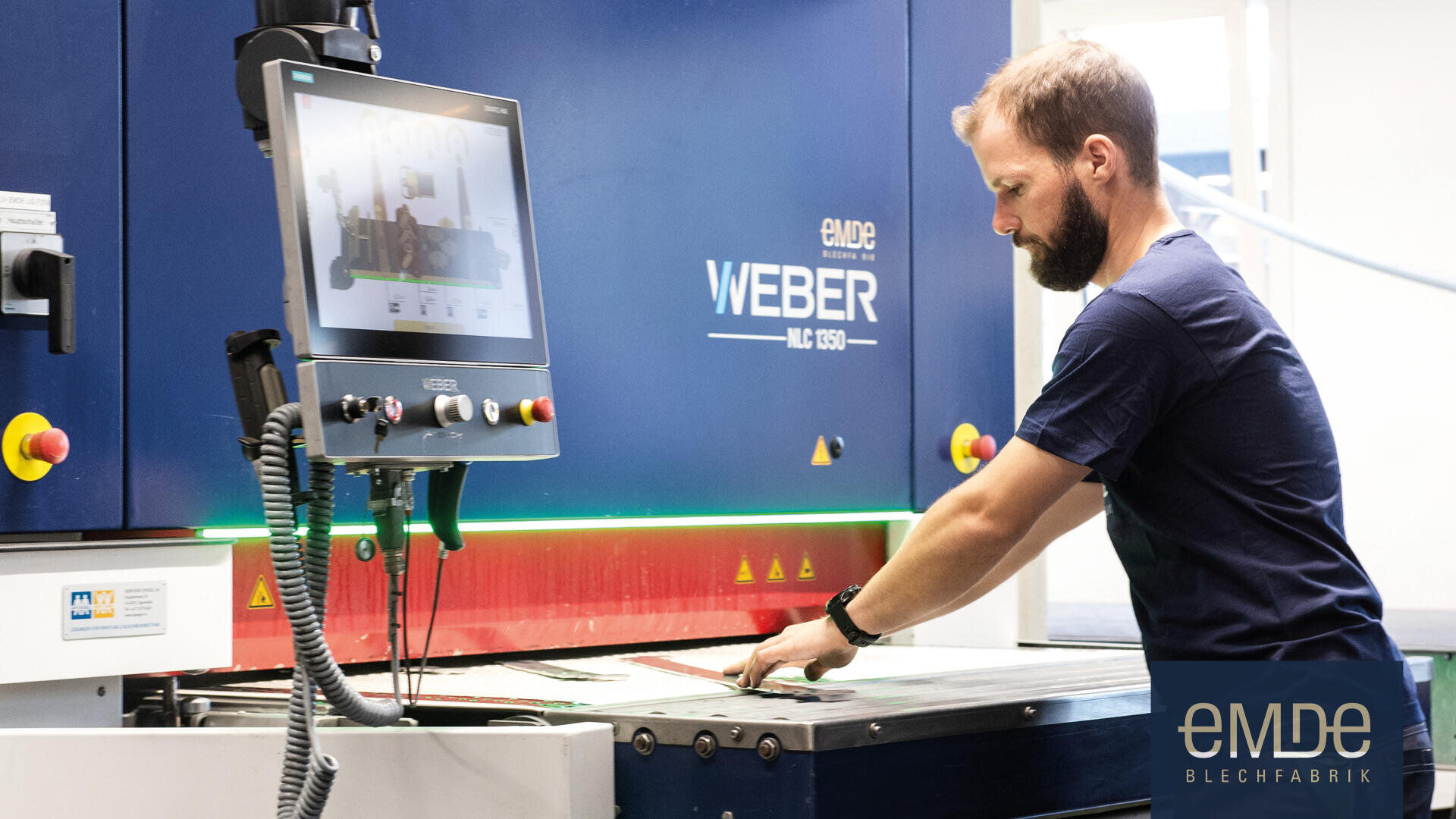 Ein Mann bedient eine große Industriemaschine mit einem Touchscreen-Display in einer modernen Fabrikumgebung. Die Maschine ist mit WEBER MLC 1350 beschriftet, und in der rechten unteren Ecke ist eMDE Blechfabrik zu sehen.