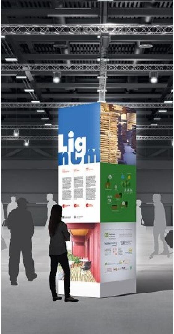 Eine Person steht vor einem hohen, rechteckigen Display mit farbenfrohen Tafeln und Text, das sich in einem großen überdachten Ausstellungsraum mit Oberlicht und anderen silhouettierten Figuren in der Nähe befindet.