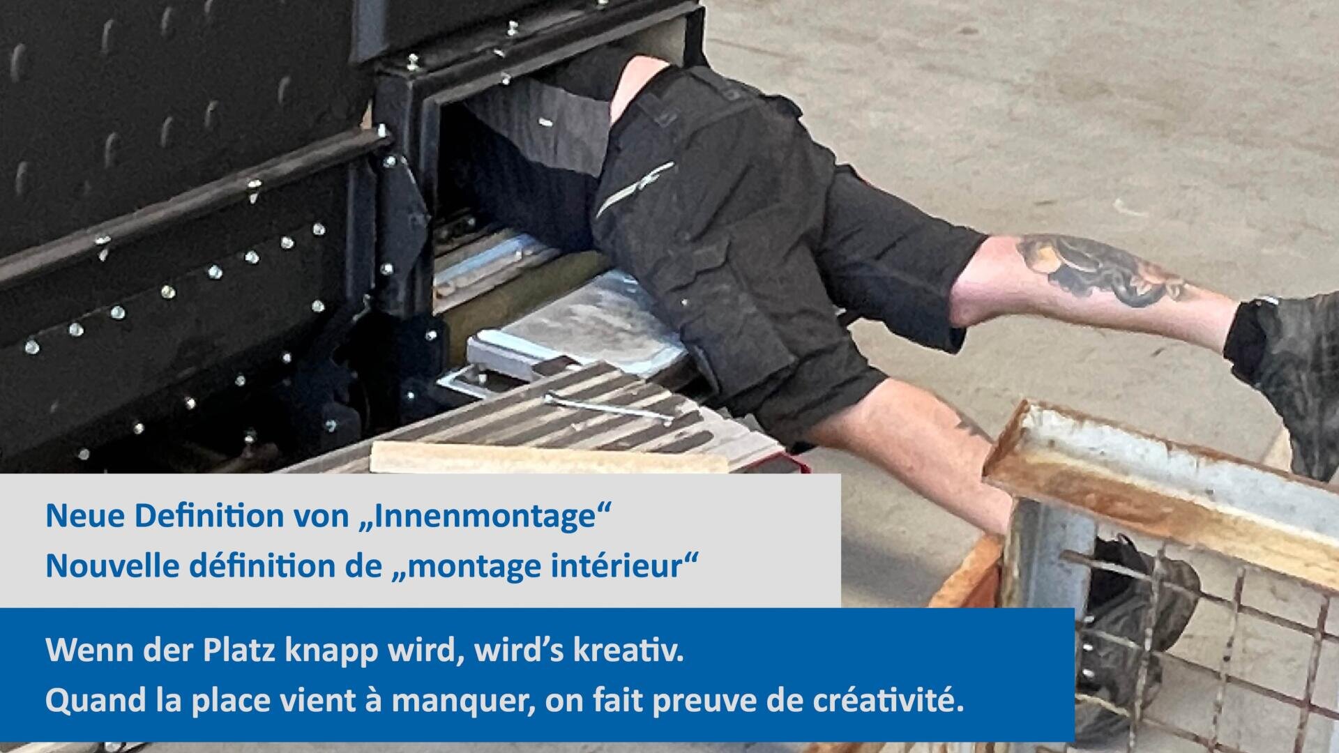 Une personne est allongée sur le ventre à l'intérieur d'une machine, travaillant dans un espace restreint, les jambes et le mollet tatoué étant visibles. Le texte en allemand et en français traite de la créativité lorsque l'espace est limité.