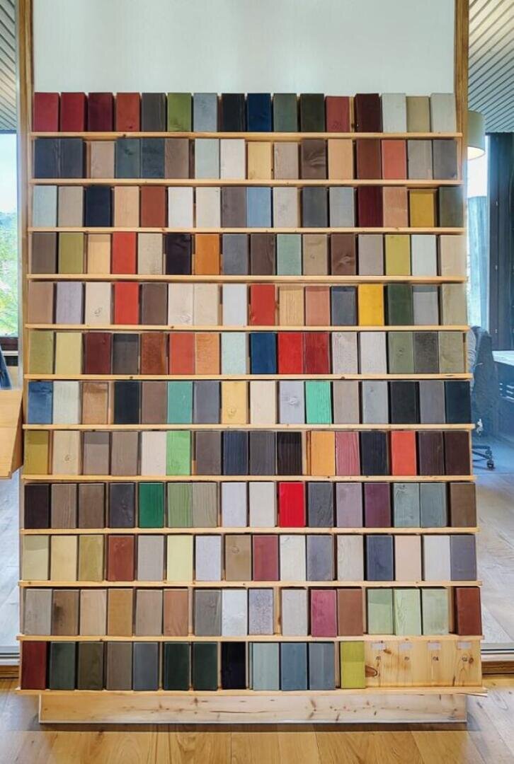 Ein Holzregal, das mit kleinen rechteckigen Blöcken gefüllt ist, jeder in einer anderen Farbe bemalt und in einem Gittermuster angeordnet. Die Blöcke zeigen eine große Vielfalt an Farbtönen und schaffen eine lebendige und organisierte Präsentation.