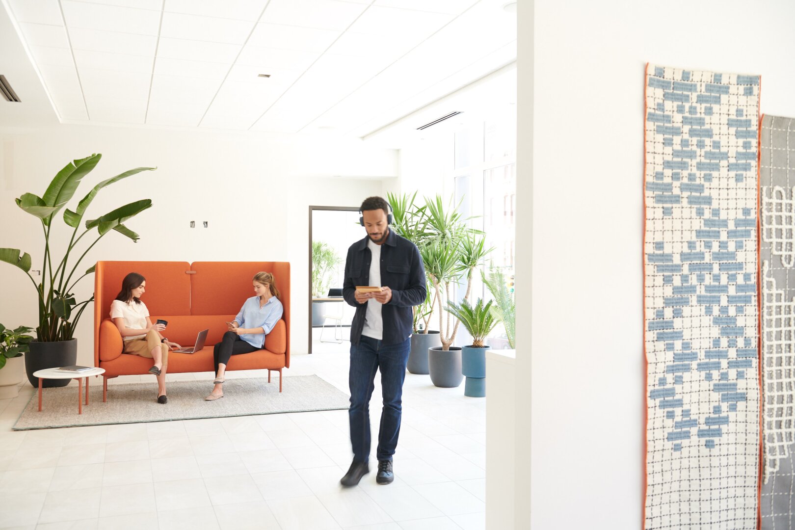 Ein Mann steht in einem Raum, in dem ein paar Leute auf einer Couch sitzen.