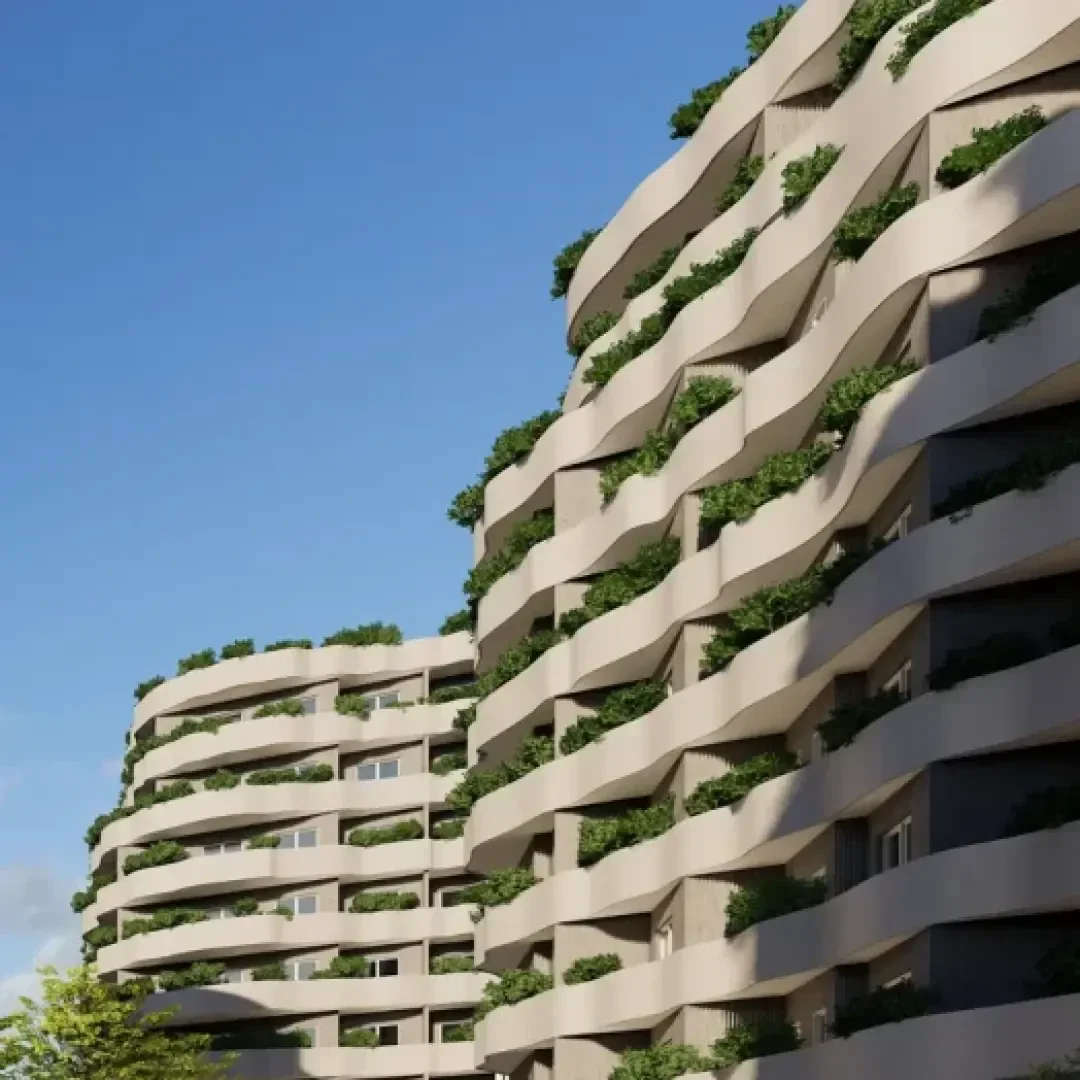 Moderne Wohnhäuser mit gewellten, beigen Fassaden. Jeder Balkon ist mit üppigen Grünpflanzen bepflanzt, die einen vertikalen Garteneffekt erzeugen. Der Himmel ist klar und blau, und im Vordergrund ist ein Baum zu sehen.