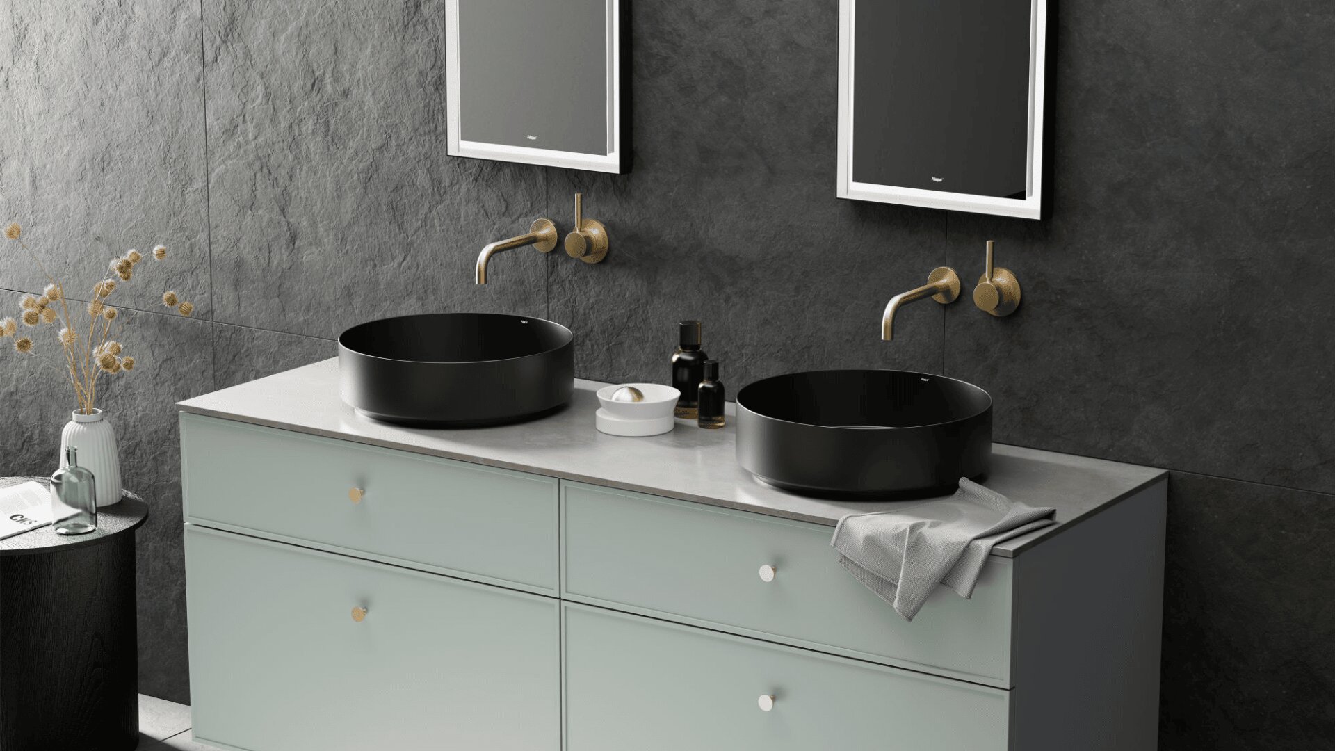 Modernes Badezimmer mit zwei runden schwarzen Waschbecken, Wandarmaturen aus Messing, einer hellen Arbeitsplatte, hellgrauen Schubladen und zwei Spiegeln an einer dunklen strukturierten Wand. Dekorative Flaschen und getrocknete Blumen sind ebenfalls zu sehen.