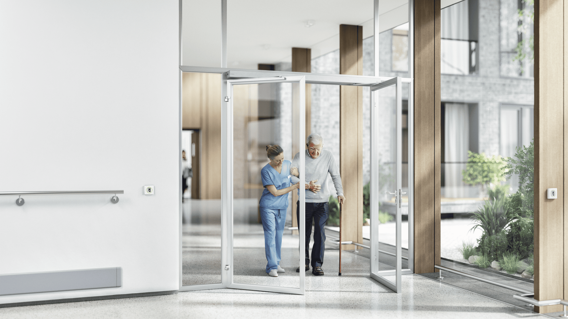 Eine Krankenschwester unterstützt einen älteren Mann, während sie durch eine Glastür in einer hellen, modernen Gesundheitseinrichtung mit großen Fenstern und natürlichem Licht gehen.
