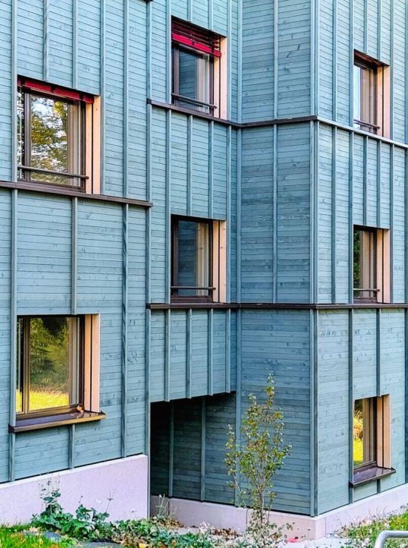 Farbig lasierte, geschlossene Holzfassade in Zürich-Wollishofen. Sie schafft Struktur, gliedert die Fläche 
und hinterlässt einen freundlichen Eindruck. 