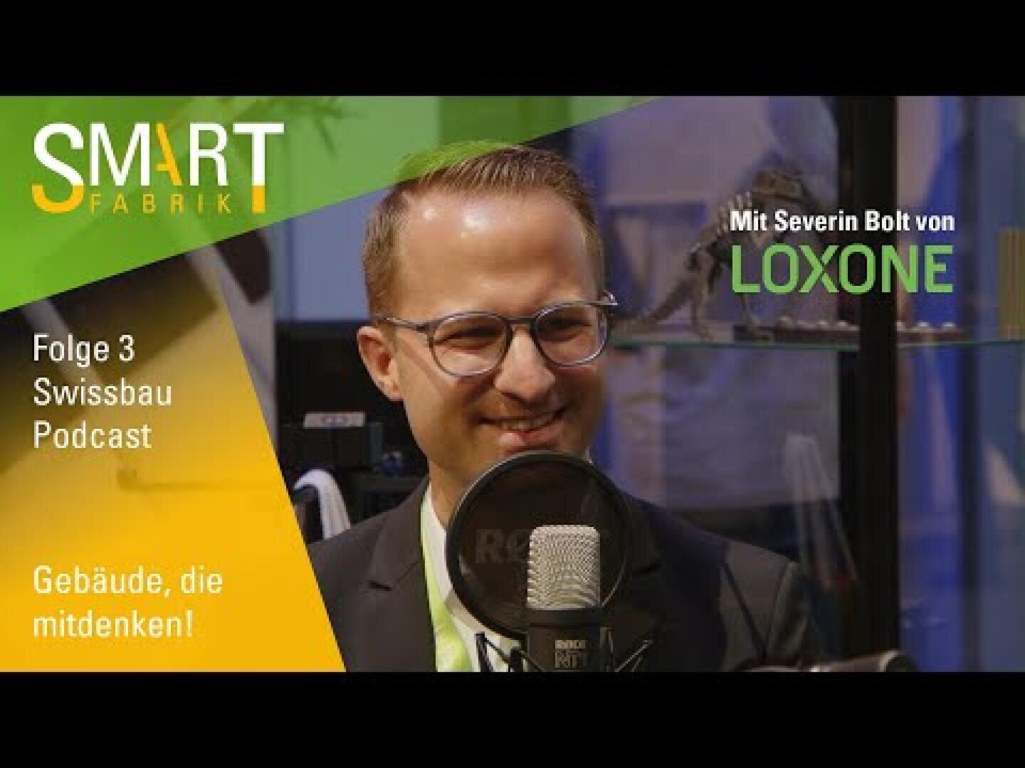 Ein Mann mit Brille sitzt während einer Podcast-Aufnahme lächelnd vor einem Mikrofon. Der Text auf dem Bild lautet: SMART FABRIK, Folge 3 Swissbau Podcast, Gebäude, die mitdenken! und Mit Severin Bolt von LOXONE.