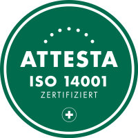Grünes kreisförmiges Abzeichen mit weißem Text "ATTESTA ISO 14001 ZERTIFIZIERT" und einem kleinen weißen Kreuz in einem Kreis am unteren Rand. Gepunkteter Bogen oberhalb des Haupttextes.