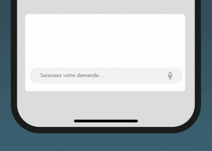Gros plan d'un écran de smartphone montrant un champ de saisie de texte avec l'espace réservé en français "Saisissez votre demande..." et une icône de microphone, suggérant une saisie vocale ou textuelle. Le bord inférieur du téléphone est visible.